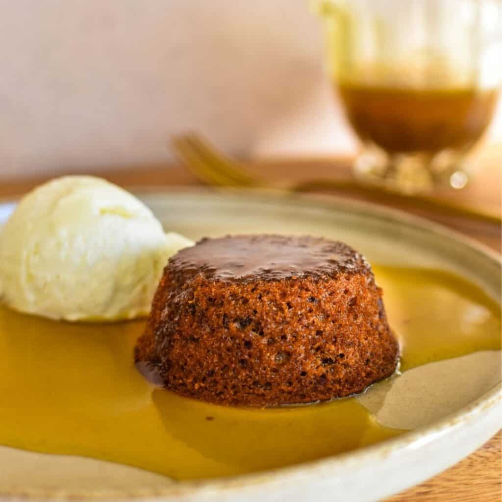 sticky date pudding on plate with sauce.