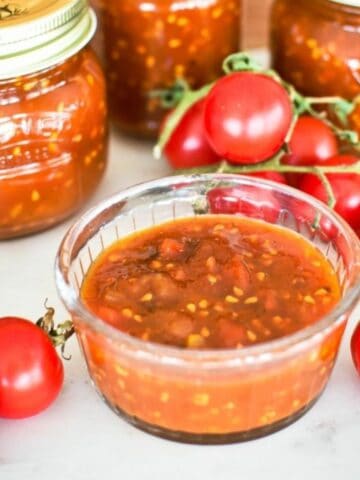 Tomato Relish in dish with jars in abckground.