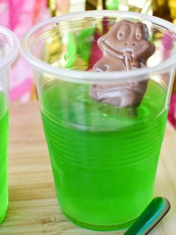 frog in a pond dessert, made of a chocolate frog sitting in green jelly in a clear plastic cup.