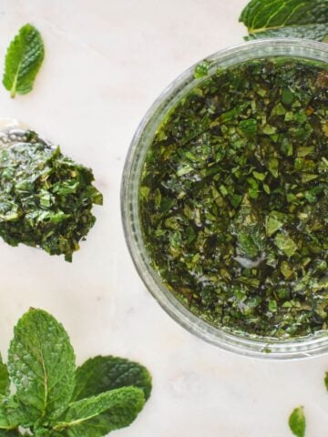 mint sauce in dish surrounded by mint leaves.