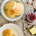 pikelets on plate served with butter and jam.
