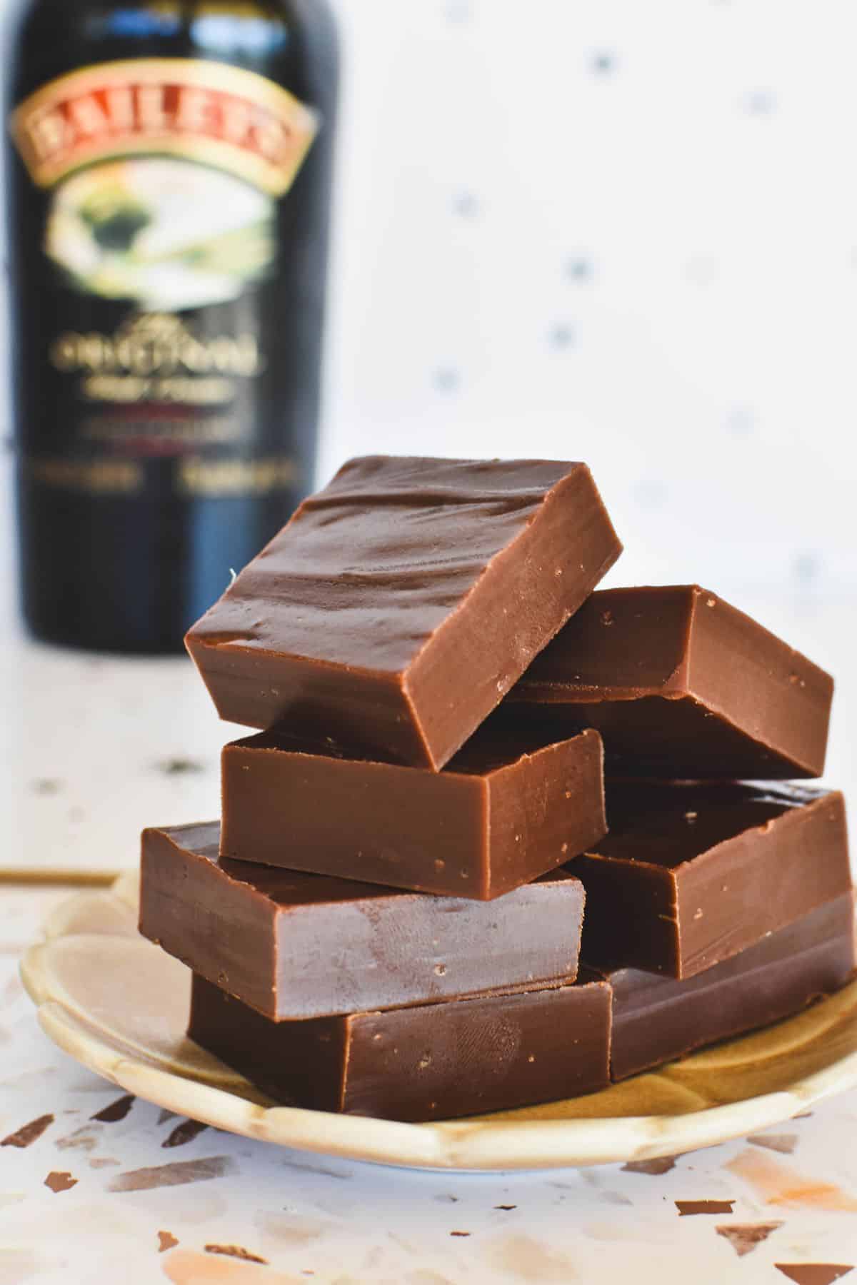 Bailey's Fudge squares on plate with Bailey's Irish Cream bottle on background.