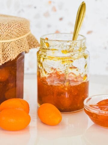 Kumquat Jam in jar with kumquats scattered on bench.
