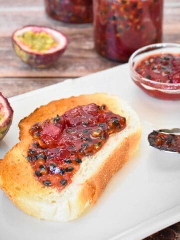 Passionfruit Jam on toast with jam jar in background.
