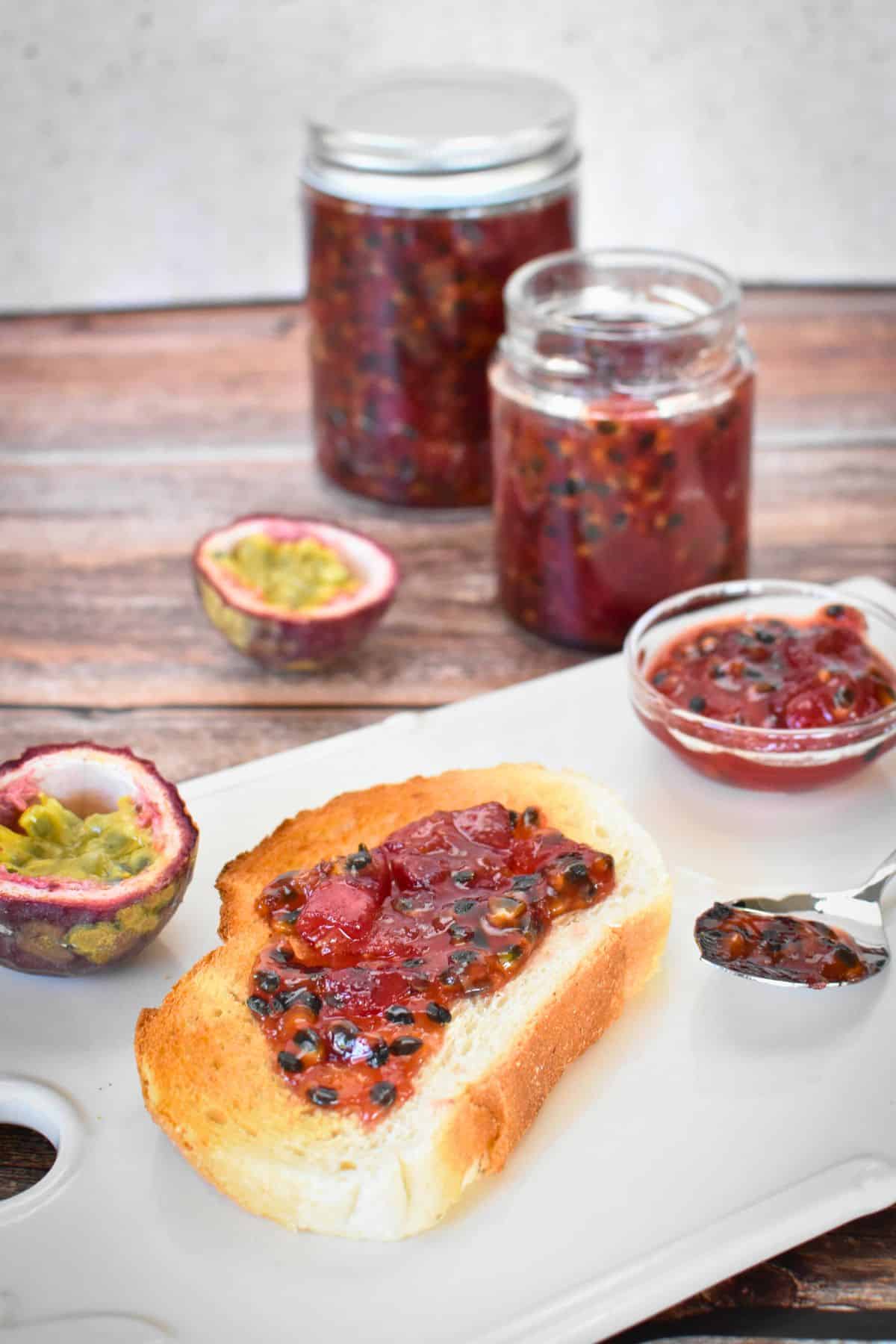 Passionfruit Jam on toast with jars of jam in background.