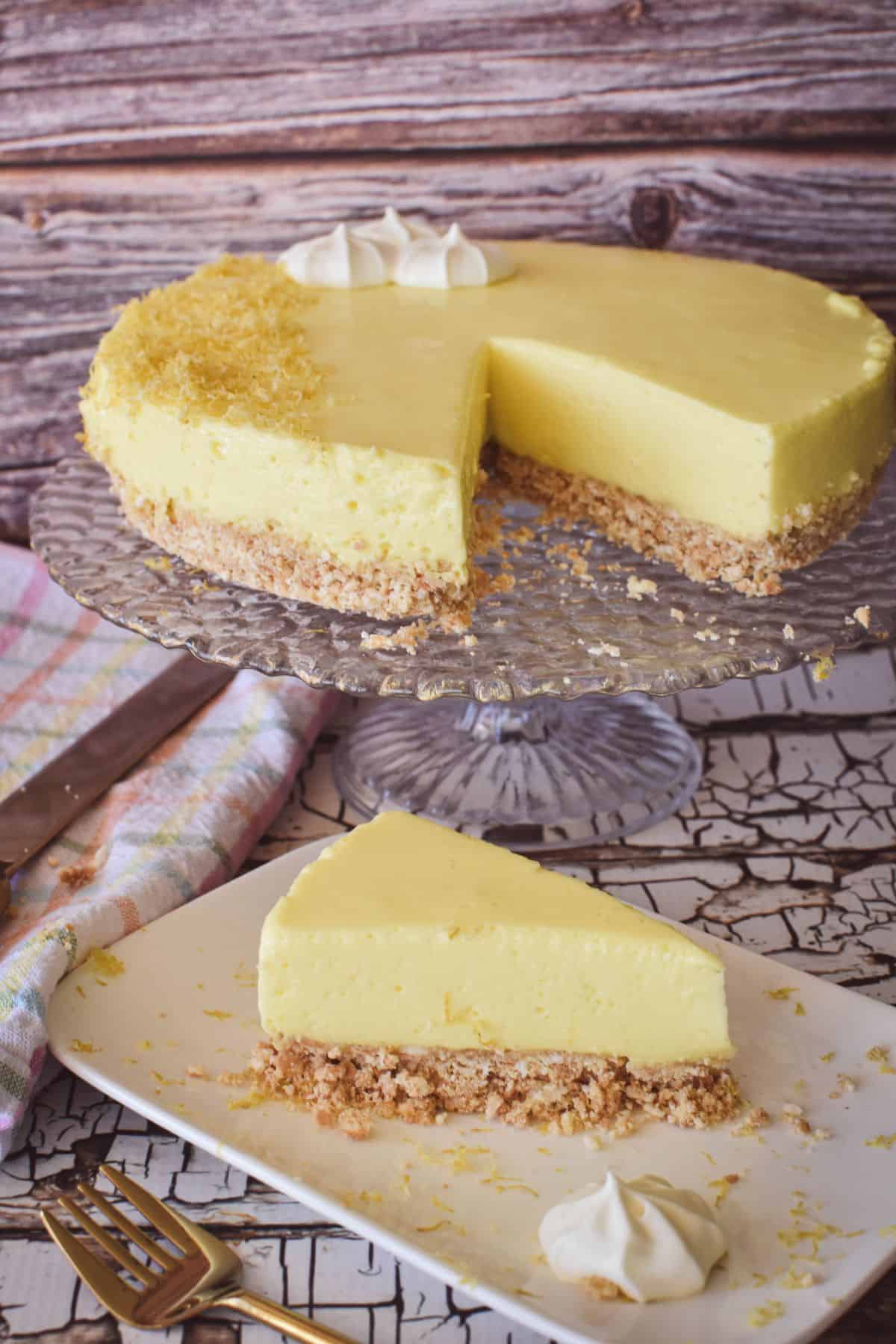 Lemon No Bake Cheesecake on cake stand with slice in foreground.