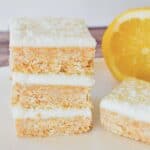 No Bake Lemon slice stacked on plate with lemon in background.