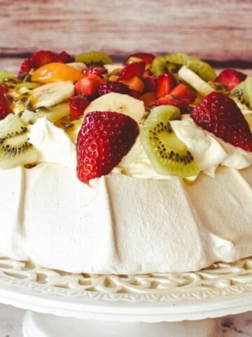 Pavlova decorated with cream and fruit.